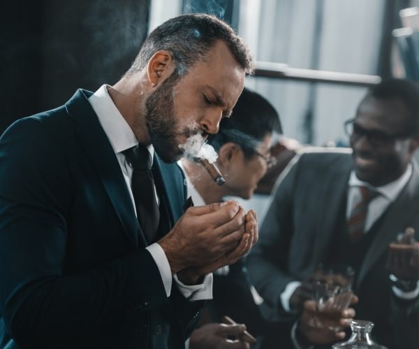 businessman smoking cigar with multicultural business team spending time behind businessman smoking cigar with multicultural business team spending time behind